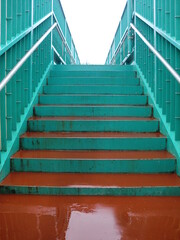 青緑と赤茶色の雨に濡れた歩道橋