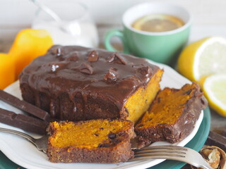 Festive homemade chocolate pumpkin long rectangular cupcake glazed with chocolate. Wooden table.