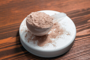 Scoop of whey or soy protein isolate on wooden table