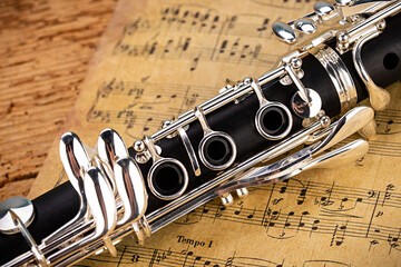 black wooden clarinet  silver woodwind musical brass instrument with old vintage music sheet paper...