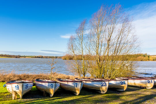 A row of  boats on the shoreline of  Pitsford Reservoir, UK on a sunny day