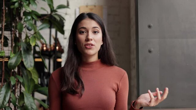 Smiling young female tutor talking to web camera. Recording vlog, online video conference, video call, online education, lessons, lecture. Job interview, online training. Webcam view