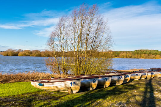 A line of  boats on the shoreline of  Pitsford Reservoir, UK on a sunny day