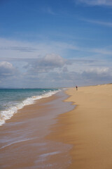 Fisherman fishing on a Comporta empty beach with ocean waves on the sand in Portugal
