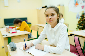 A student at school at the lesson at the table with a pencil case and a book. Schooling