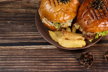 Two freshly fried burgers lie on a plate and a wooden table against the background of a fireplace. Juicy fried dinner in front of fireplace
