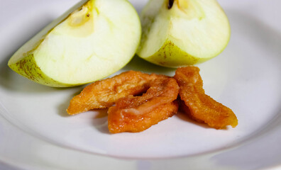 Slices of fresh green apple on a plate and next to them are dried apple slices.