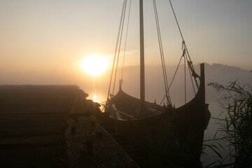 Mystic viking vessel at the jetty with fog at sunrise.
