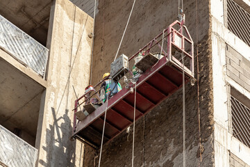 Construction cradle hanging at the wall of a house under construction