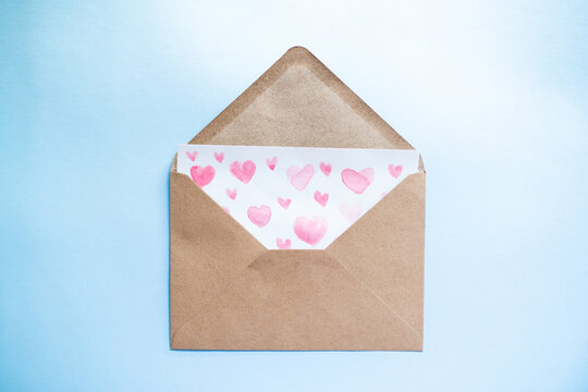 Love letter with water color pink hearts in a craft envelope on blue background. - Powered by Adobe