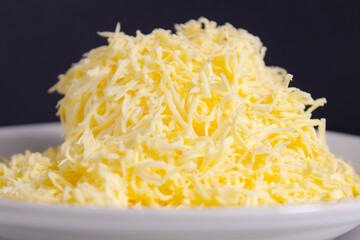 grated hard cheese on a light plate close-up.