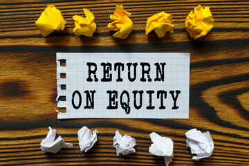 On a wooden board lie crumpled leaves of paper and a sheet from a notebook on which it is written - RETURN ON EQUITY