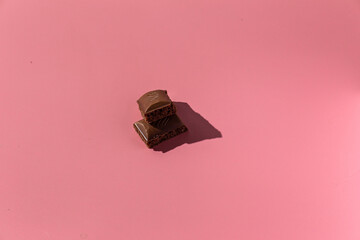 pieces of chocolate on a pink background with hard light