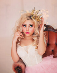 Portrait capricious princess girl. Blond hair. lady woman sitting in vintage armchair. Fairy tale white room. Woman Queen straightens gold crown on head with hand. surprised face, pink lips blue eyes © kharchenkoirina
