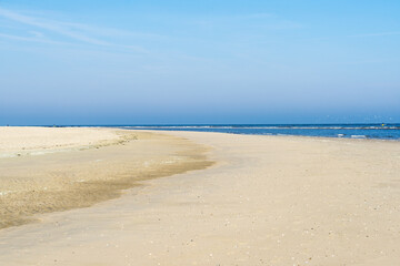 Fototapeta na wymiar Yellow empty beach at the Dutch North Sea in summer with blue sky and sea