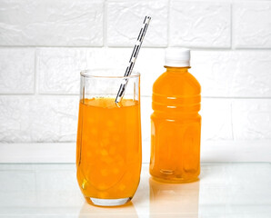 Juice with pieces of fruit in a glass and a plastic bottle.