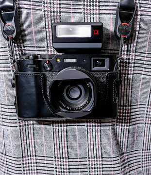 Norwich, Norfolk, UK &ndash; December 28 2020. An illustrative photo of a close up of a Fuji X100 rangefinder camera on the neck strap of an unidentifiable female photographer