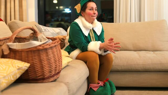 A woman dressed as an elf waits for the children before performing in the room. Makes movement with fingers, manifestation of nervous behavior, excitement.