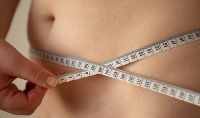Woman measures her waist line. Woman wants to lose weight. Diet and healthy eating. Overweight...