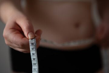 Woman measures her waist line. Woman wants to lose weight. Diet and healthy eating. Overweight women isolated