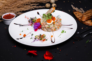 Fototapeta na wymiar interpretation of olivier salad with grilled chicken fillet, quail eggs and red caviar, on a dark background.