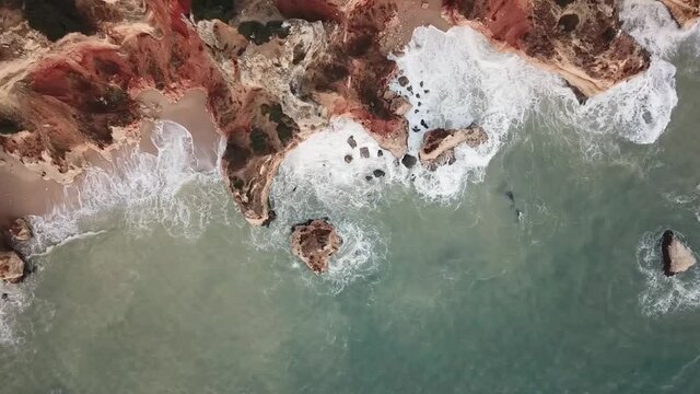 Lagos Portugal Atlantic ocean drone shot aerial view look over blue water waves sunrise morning limestone coastline sea pillars hidden grottos Praia do Camilo camera down fly sideways shore coast 