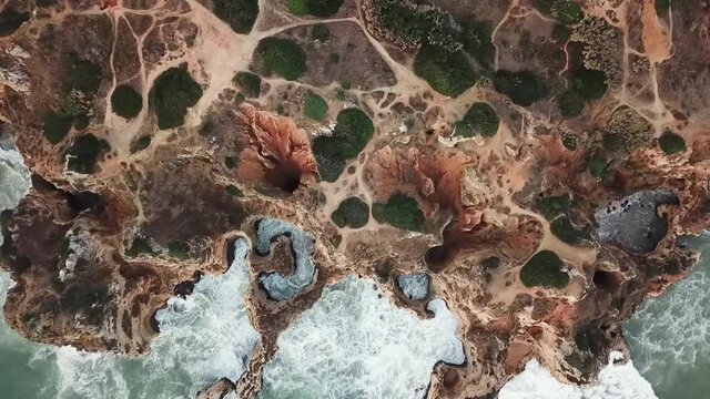 Lagos Portugal Atlantic ocean drone shot aerial view look over the rocks blue water waves sunrise morning limestone coastline sea pillars hidden grottos Praia da Boneca fly up left sideways 