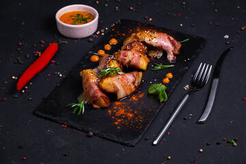 Baked jacket potatoes slices of bacon with honey-mustard sauce, on a dark background