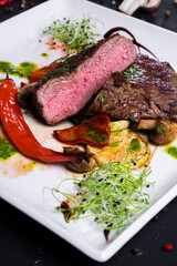 Ribeye steak with Grilled vegetableson on a white plate on dark background