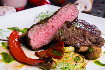 Ribeye steak with Grilled vegetableson on a white plate on dark background