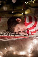 Obraz na płótnie Canvas Boy sleeping under Christmas tree