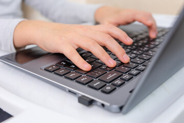 focused little kids hands pressing laptop keyboard
