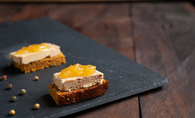 Foie gras toasts with candied onion and gingerbread on a slate