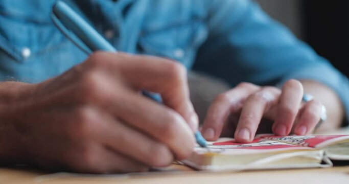 Close Up of Males Hand is drawing some Comix Woman on the Paper. Artist Man is drawing Female Portrait concentrated, enjoying the Process. Creative Person, People Profession.