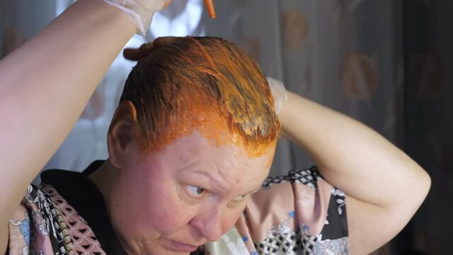 Putting on the dye chemicals onto the hair of the lady