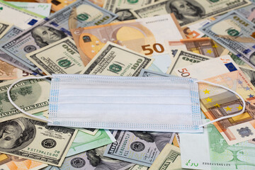 medical mask on dollar and euro banknotes background