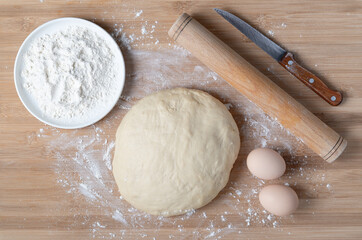 Top view of dough and baking ingredients on wooden table