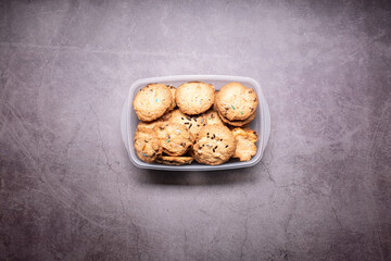 Some handmade cookies made at home on a plastic recipient box close up still isolated on a grey background