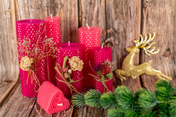 Handmade pink honey candles made of natural wax on a background of wooden boards. Elements from natural materials. Christmas or New Year's composition. Photo for postcards.