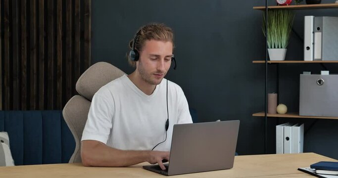 Young Handsome Businessman, Freelancer is chatting on Laptop, working Online. Young Successful Man is working from Home Office, surfing, sharing Positive Emotions. Online Job, Working Indoor.