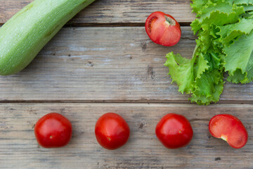 Tomatoes, zucchini and green lettuce leaves on a wooden table