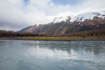 Snow capped mountains in clouds and blue waters of Portage Creek, Alaska