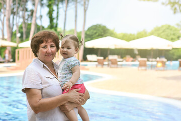 Happy smiling grandmother and cute adorable baby granddaughter on the resort. Tourism and family holiday concept. Sweet and happy moments. Family generation, Family time and Happy childhood.