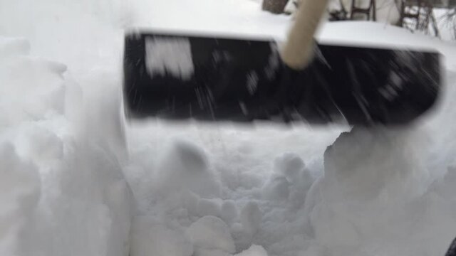 Close-up of a shovel, a man cleans snow with a shovel in his yard. Winter in Russia covered the yard with snow