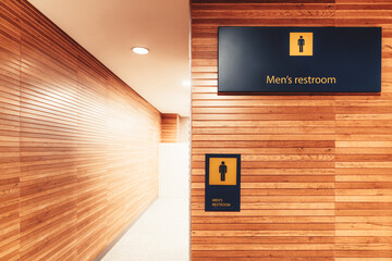 A bright interior with a wood cladding of a modern entrance to a public men toilet in an airport...