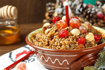 kutya, porridge from wheat with honey, nuts and berries, a traditional treat on Christmas Eve. Close-up, with a fir wreath in the background