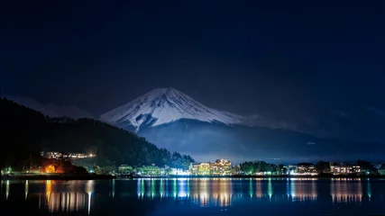 Papier Peint photo Mont Fuji Superbe panorama sur le Mont Fuji vue de nuit depuis le lac de Kawagushiko avec la ville d'Oishi éclairée, Japon