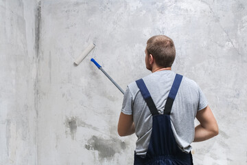 A male worker primes the wall with a roller for better grip.