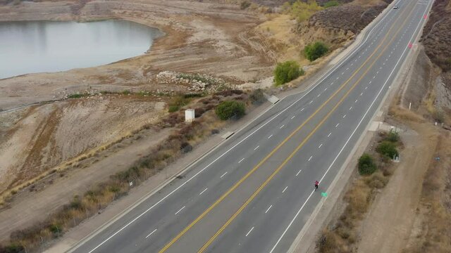 Aerial shot of Cyclist on the street next to Forest and Lake in California