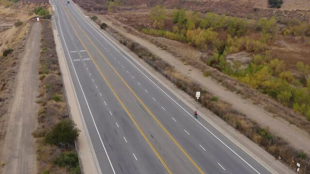 Drone shot Biking on the street next to Forest and Lake in Orange County